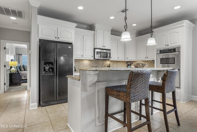 kitchen with white cabinetry, appliances with stainless steel finishes, light stone countertops, and a kitchen island