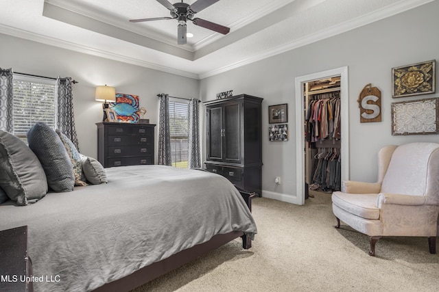 bedroom with crown molding, a tray ceiling, carpet floors, and a spacious closet