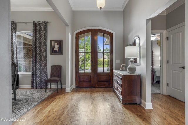 entrance foyer with light hardwood / wood-style flooring, ornamental molding, and french doors