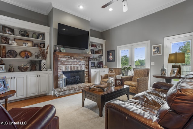 living room with french doors, ornamental molding, ceiling fan, a fireplace, and light hardwood / wood-style floors