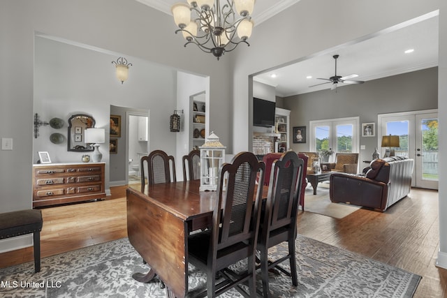 dining space with crown molding, wood-type flooring, french doors, and a towering ceiling