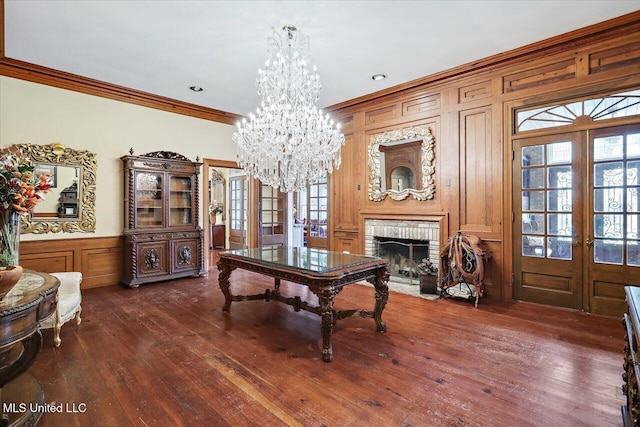 interior space with dark wood-type flooring, french doors, ornamental molding, a fireplace, and a chandelier