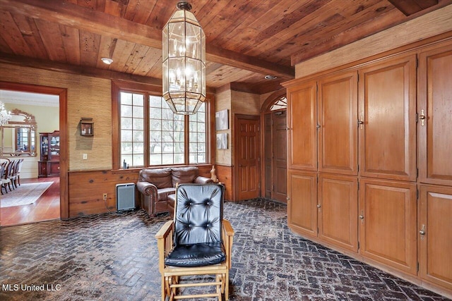 living area with beam ceiling, wooden walls, and an inviting chandelier