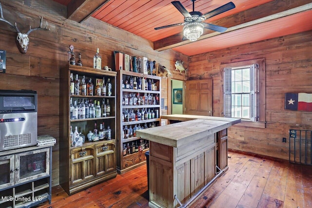 bar with beam ceiling, wood walls, hardwood / wood-style floors, and butcher block countertops