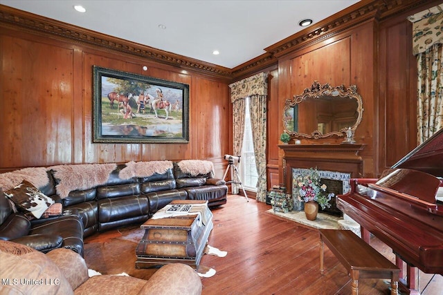 living room with hardwood / wood-style floors, wood walls, crown molding, and a high end fireplace