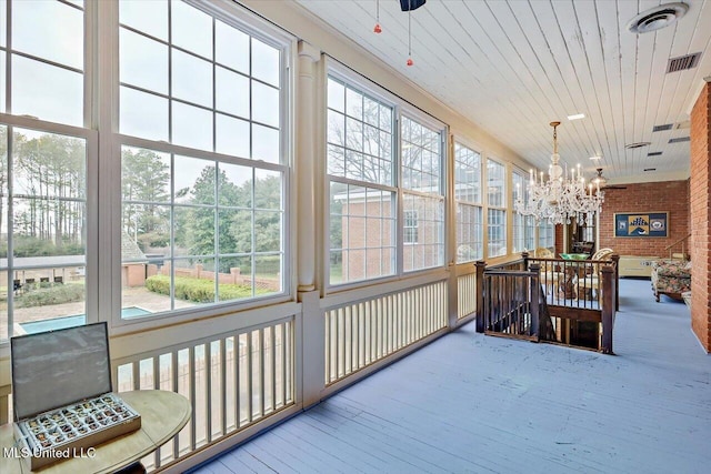 sunroom / solarium featuring plenty of natural light, wooden ceiling, and an inviting chandelier