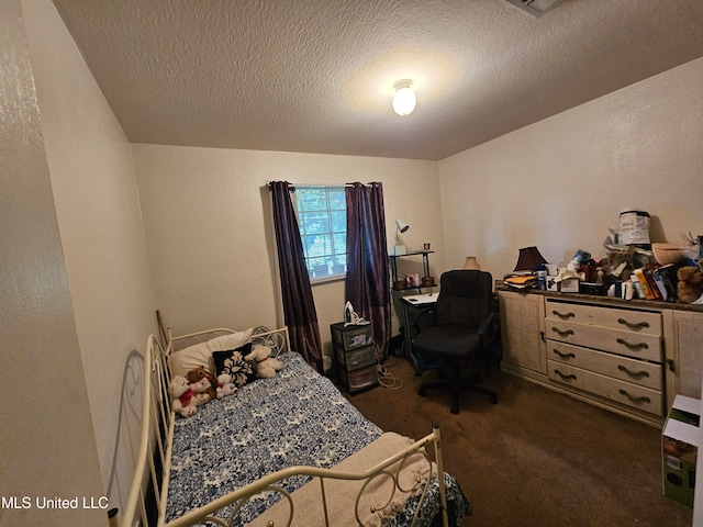 bedroom featuring a textured ceiling and dark colored carpet