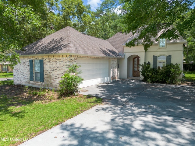 796 Hapuna Pl, Diamondhead, MS 39525 - french country style house featuring brick siding, a garage, driveway, roof with shingles, and stucco siding
