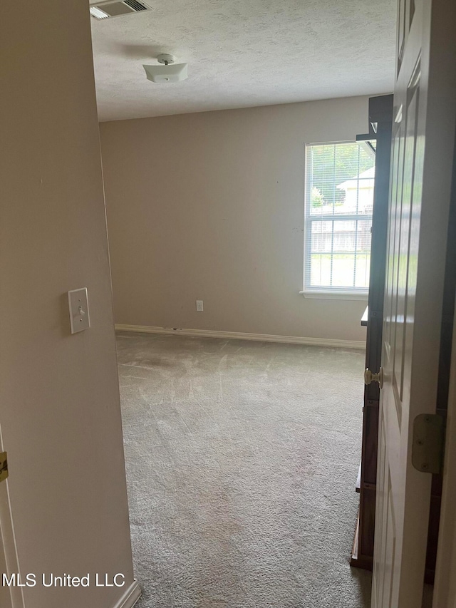 unfurnished room with a textured ceiling and carpet floors