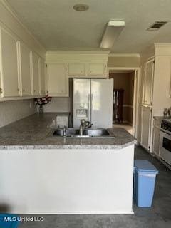 kitchen with sink, stainless steel range, kitchen peninsula, and white fridge with ice dispenser