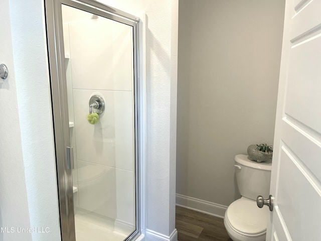 bathroom featuring hardwood / wood-style flooring, toilet, and a shower with shower door