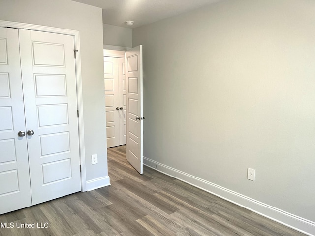 unfurnished bedroom with dark wood-type flooring and a closet