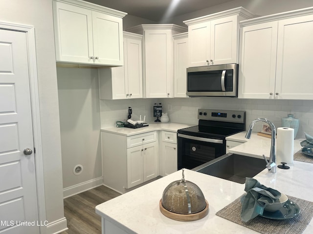 kitchen featuring sink, black electric range, decorative backsplash, and white cabinets