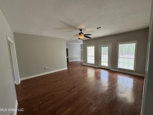 unfurnished room featuring ceiling fan, a textured ceiling, dark hardwood / wood-style floors, and a healthy amount of sunlight