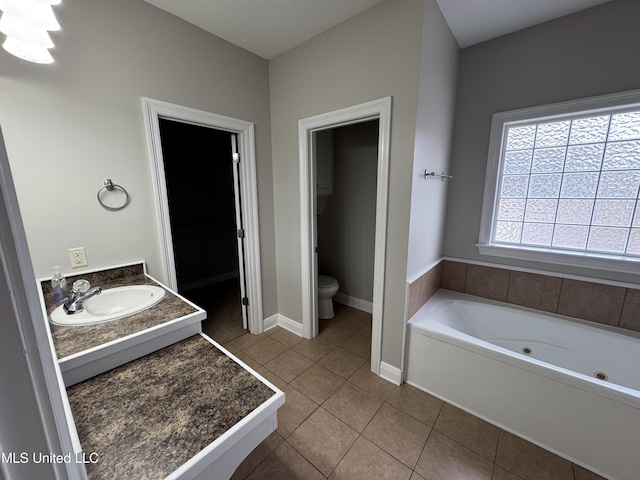 bathroom featuring tile patterned flooring, vanity, toilet, and a tub to relax in