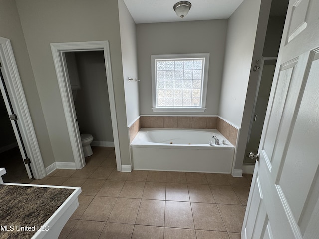 bathroom with tile patterned flooring, a bath, and toilet