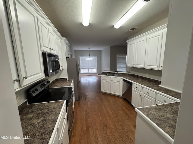 kitchen featuring pendant lighting, sink, stainless steel appliances, white cabinets, and kitchen peninsula