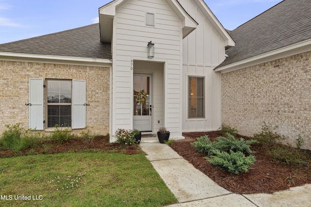970 Glenwild Cir, Canton, MS 39046 - property entrance featuring board and batten siding, roof with shingles, a lawn, and brick siding