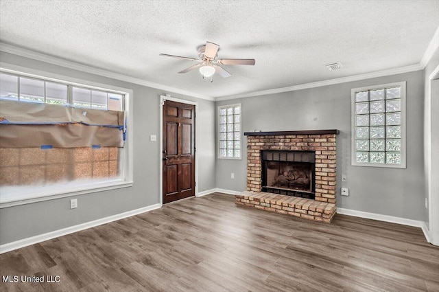 unfurnished living room featuring ornamental molding, hardwood / wood-style floors, a brick fireplace, and a textured ceiling