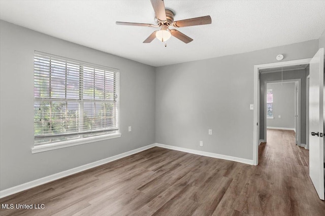 empty room with hardwood / wood-style flooring, ceiling fan, and a healthy amount of sunlight