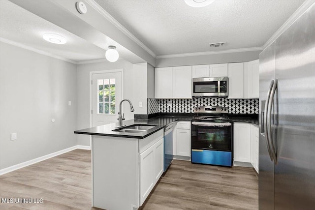 kitchen with stainless steel appliances, kitchen peninsula, sink, and white cabinets