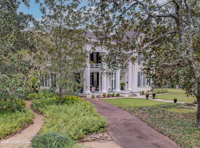 neoclassical home featuring a balcony, a front lawn, and a porch