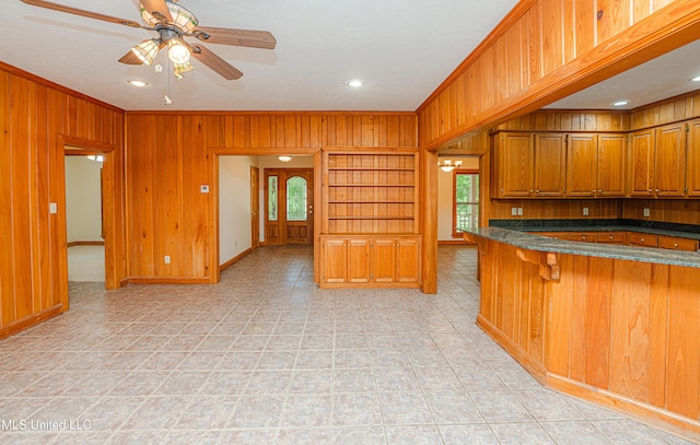 4005 Warriors Trl, Vicksburg, MS 39180 - kitchen featuring wood walls, brown cabinets, ornamental molding, baseboards, and ceiling fan