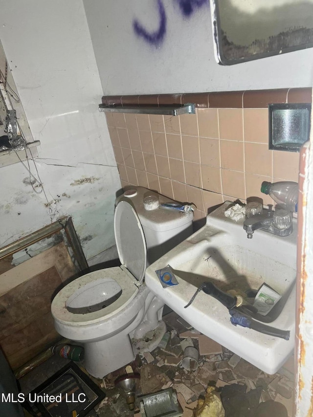 bathroom with toilet, tile walls, and sink