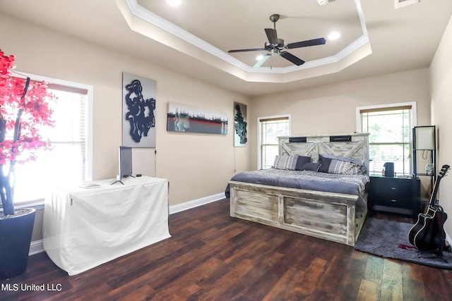 bedroom featuring crown molding, a tray ceiling, dark wood-type flooring, and ceiling fan