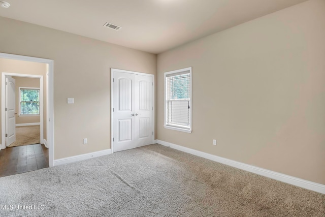 unfurnished bedroom featuring hardwood / wood-style floors, multiple windows, and a closet