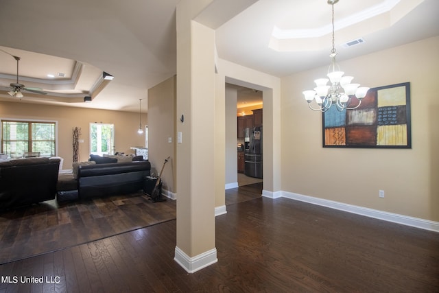 interior space with ornamental molding, dark hardwood / wood-style floors, ceiling fan with notable chandelier, and a raised ceiling