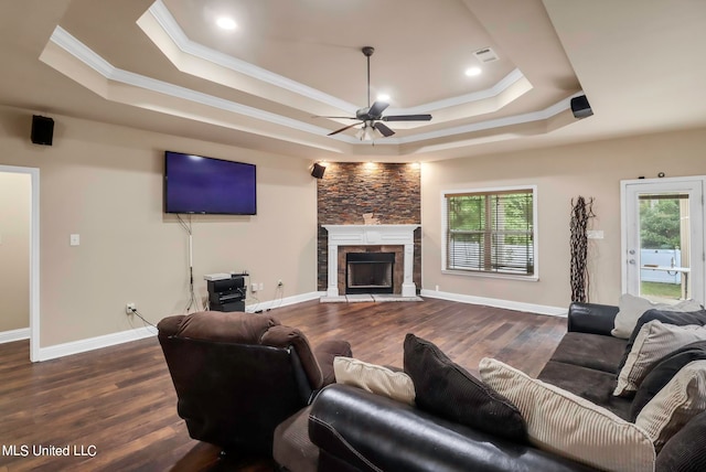 living room with a raised ceiling, ceiling fan, a fireplace, and dark hardwood / wood-style flooring