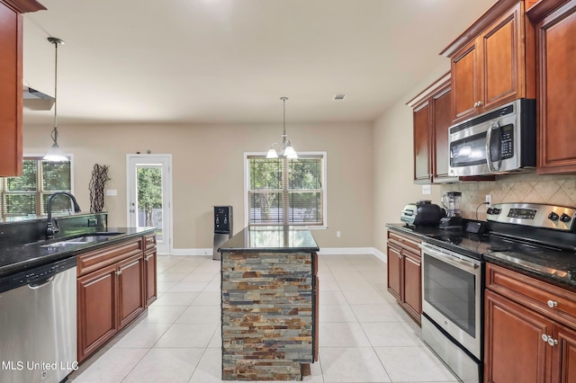 kitchen featuring stainless steel appliances, sink, light tile patterned flooring, and decorative light fixtures