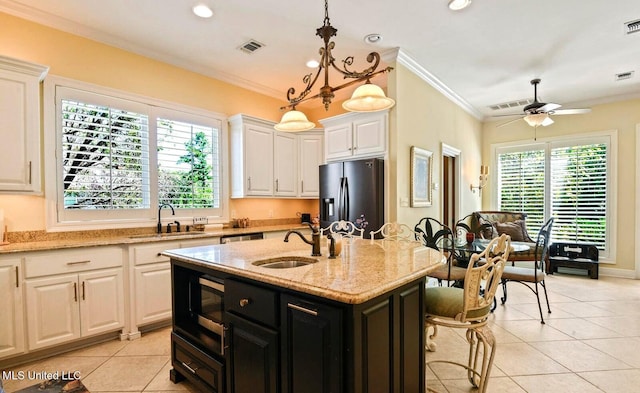 kitchen featuring sink, a center island with sink, stainless steel fridge, ceiling fan, and white cabinets