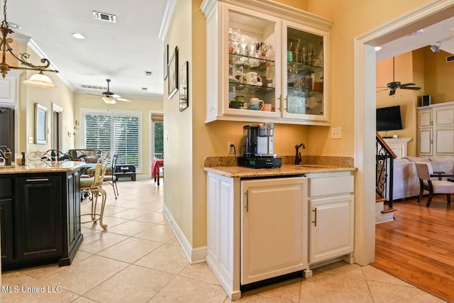 kitchen with light tile patterned floors, crown molding, sink, ceiling fan, and light stone countertops