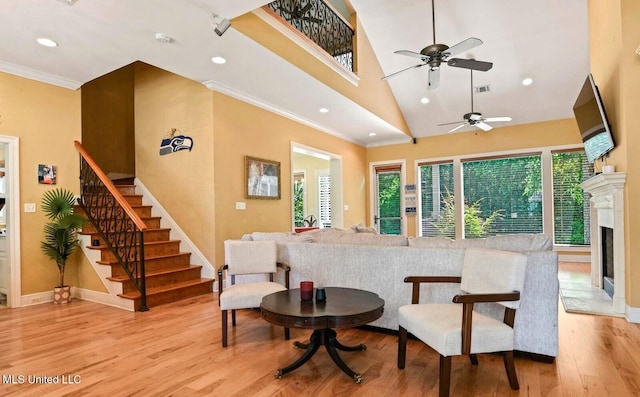 interior space with crown molding, a towering ceiling, ceiling fan, and light hardwood / wood-style flooring