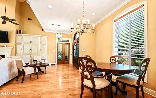 dining room with ceiling fan with notable chandelier, light hardwood / wood-style flooring, ornamental molding, and french doors