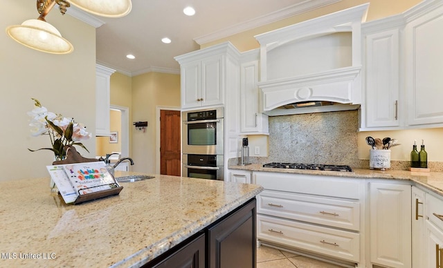 kitchen with stainless steel appliances, light stone countertops, ornamental molding, white cabinets, and decorative light fixtures