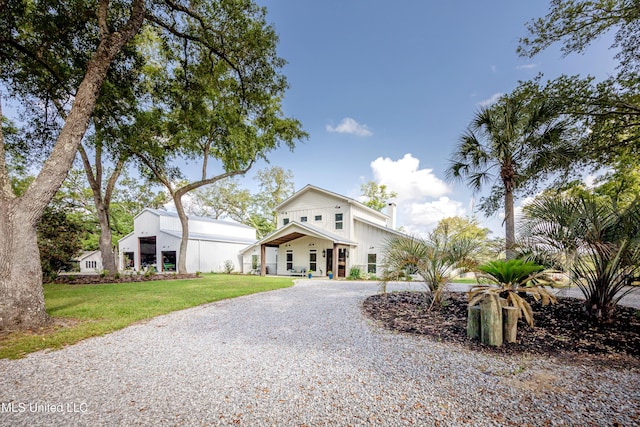 view of front facade with a chimney, a front yard, and gravel driveway