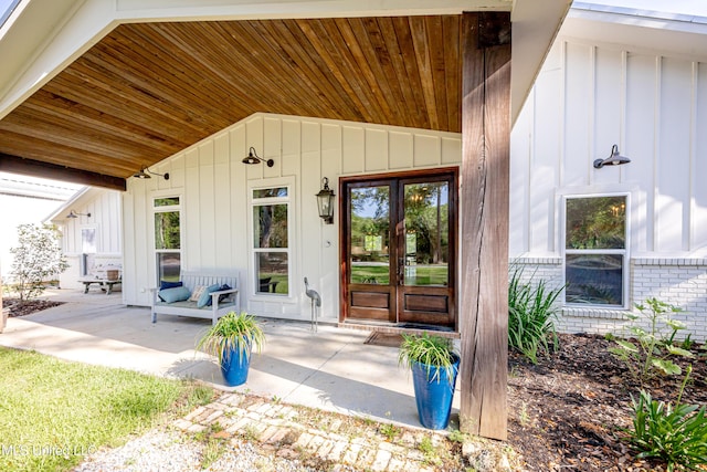 entrance to property featuring board and batten siding, brick siding, and french doors