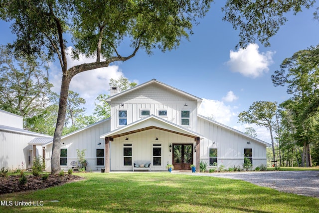 modern farmhouse style home with board and batten siding, a chimney, and a front yard