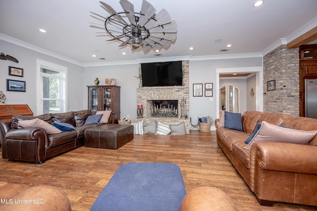living room with recessed lighting, ornamental molding, wood finished floors, and a large fireplace
