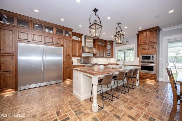 kitchen with built in appliances, a center island, brick floor, brown cabinets, and tasteful backsplash