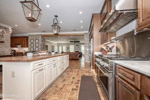 kitchen with crown molding, high end appliances, ventilation hood, open floor plan, and brick floor
