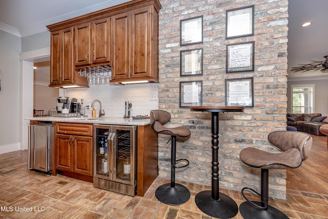 bar with a sink, brick floor, beverage cooler, and crown molding
