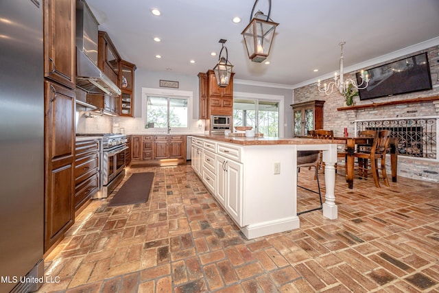 kitchen with decorative backsplash, a kitchen bar, built in appliances, brick floor, and recessed lighting