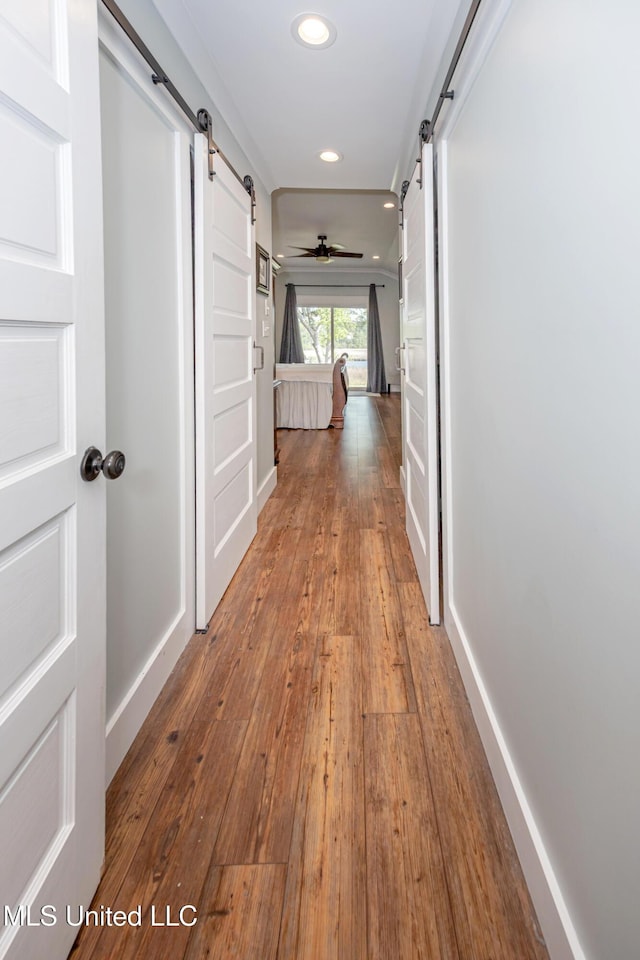 corridor with recessed lighting, baseboards, a barn door, and hardwood / wood-style floors