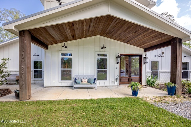 view of exterior entry featuring board and batten siding and a yard