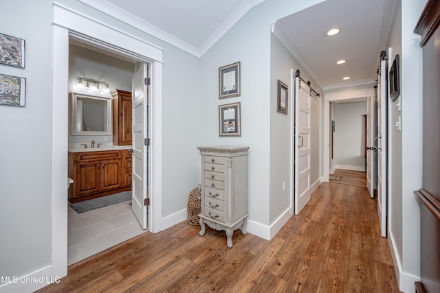 hall featuring ornamental molding, hardwood / wood-style floors, recessed lighting, a barn door, and a sink