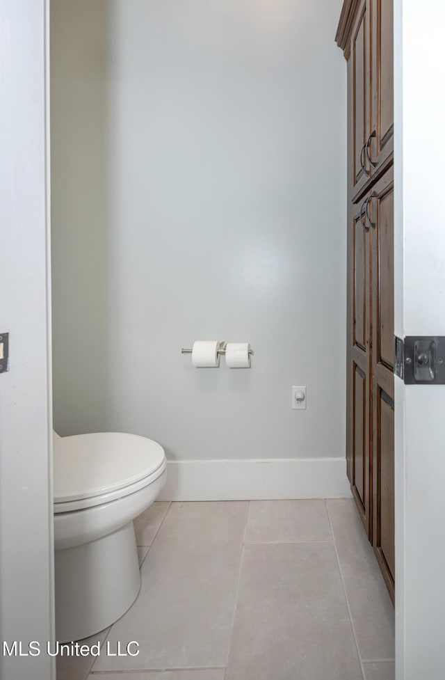 bathroom featuring baseboards, tile patterned flooring, and toilet